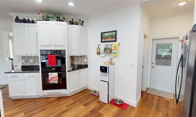 kitchen featuring light wood-type flooring, double oven, stainless steel fridge, and backsplash