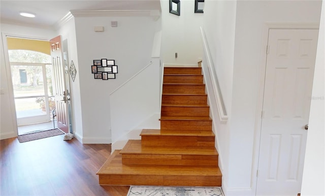 stairway with ornamental molding and wood-type flooring