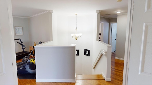 hallway with ornamental molding, light hardwood / wood-style flooring, and a notable chandelier