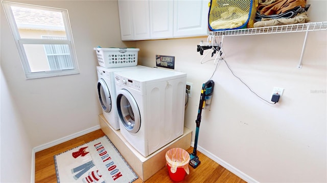 clothes washing area with light wood-type flooring, cabinets, and independent washer and dryer