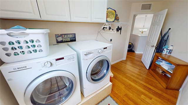 laundry room featuring light wood-type flooring, a notable chandelier, cabinets, and separate washer and dryer