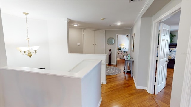 hall featuring ornamental molding, a chandelier, and light hardwood / wood-style floors