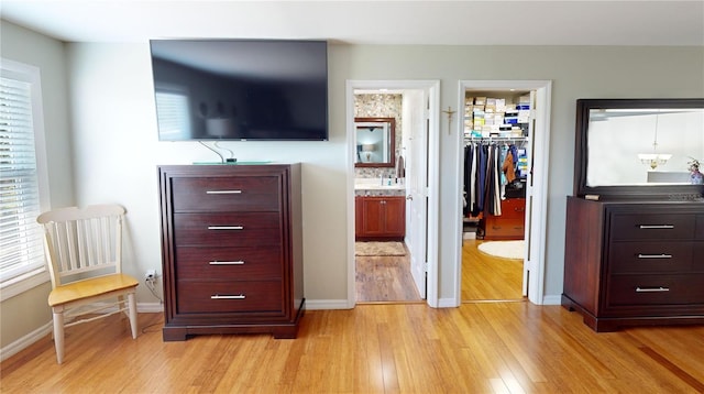 bedroom featuring a closet, a walk in closet, light hardwood / wood-style floors, and ensuite bath