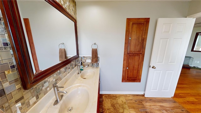 bathroom with hardwood / wood-style flooring, decorative backsplash, and vanity