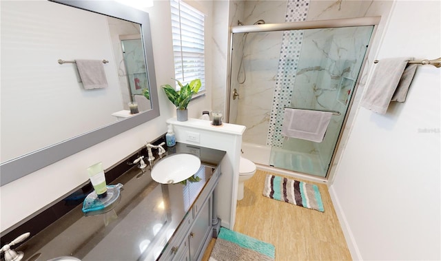 bathroom featuring vanity, toilet, wood-type flooring, and a shower with shower door