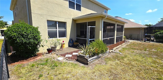 back of property with a yard and a sunroom