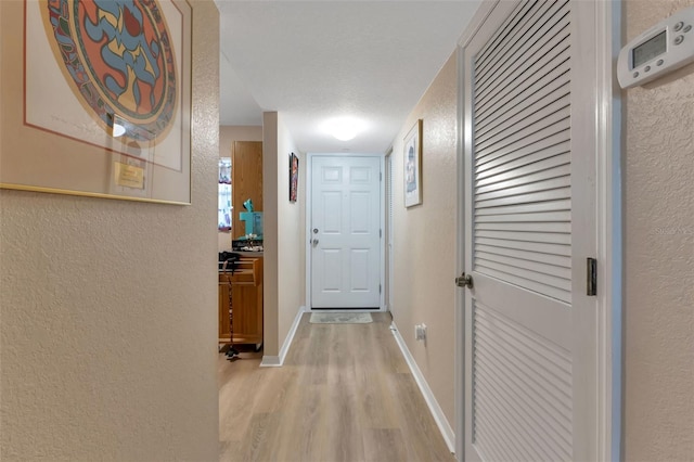 hallway featuring light hardwood / wood-style floors and a textured ceiling