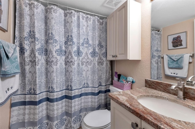 bathroom featuring vanity with extensive cabinet space and toilet