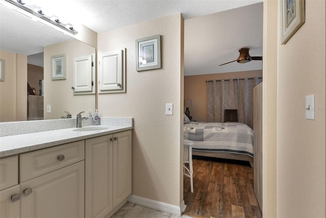 bathroom with a fireplace, vanity, hardwood / wood-style floors, ceiling fan, and a textured ceiling