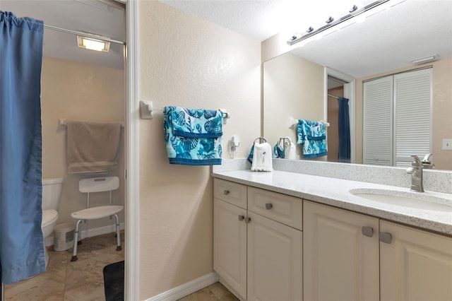 bathroom with toilet, tile floors, vanity, and a textured ceiling