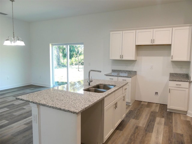 kitchen featuring light stone countertops, sink, dark hardwood / wood-style floors, a center island with sink, and white cabinets