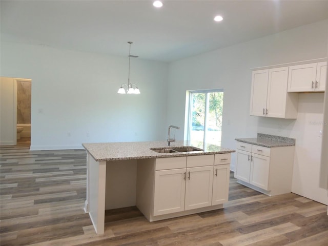 kitchen featuring white cabinets, dark hardwood / wood-style flooring, an island with sink, and sink