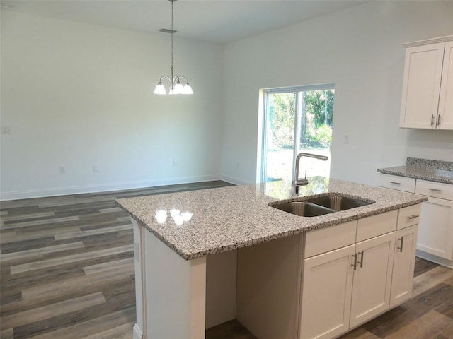 kitchen with white cabinets, dark hardwood / wood-style floors, a kitchen island with sink, and sink