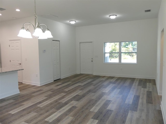 spare room with dark hardwood / wood-style flooring and an inviting chandelier