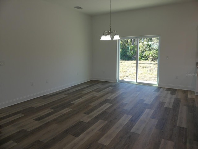 spare room with a chandelier, a high ceiling, and dark hardwood / wood-style flooring