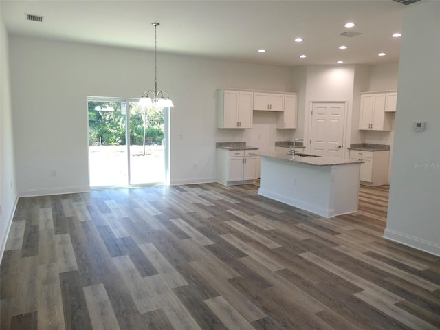 kitchen with white cabinets, sink, dark hardwood / wood-style flooring, and a kitchen island with sink