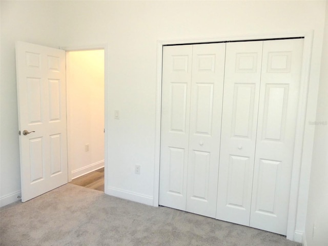 unfurnished bedroom featuring light colored carpet and a closet