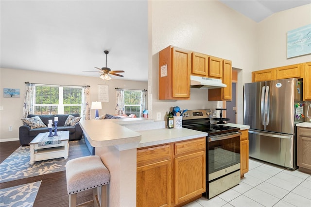 kitchen featuring a breakfast bar, stainless steel appliances, light hardwood / wood-style floors, ceiling fan, and kitchen peninsula