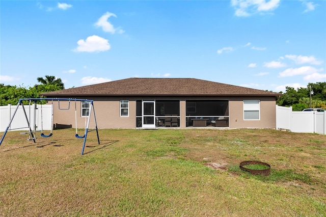 rear view of house featuring a playground and a lawn