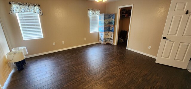 unfurnished bedroom featuring a walk in closet, dark hardwood / wood-style floors, a closet, and multiple windows