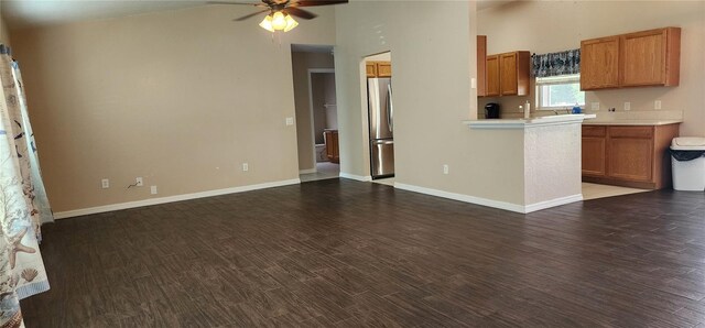 kitchen featuring ceiling fan, a high ceiling, dark hardwood / wood-style floors, and stainless steel refrigerator