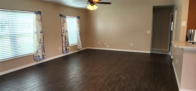 spare room with ceiling fan, dark wood-type flooring, and a healthy amount of sunlight