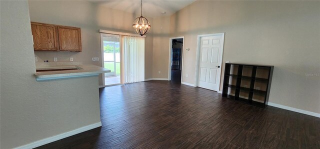 kitchen with a notable chandelier, high vaulted ceiling, dark wood-type flooring, and pendant lighting