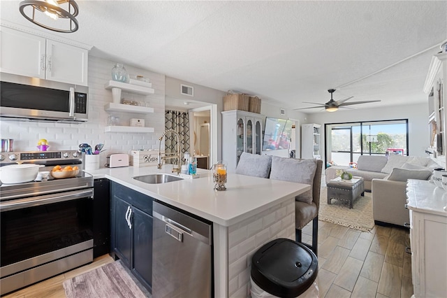 kitchen with kitchen peninsula, stainless steel appliances, white cabinetry, and tasteful backsplash