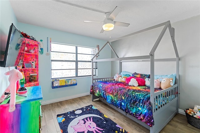 bedroom with hardwood / wood-style flooring, ceiling fan, and a textured ceiling