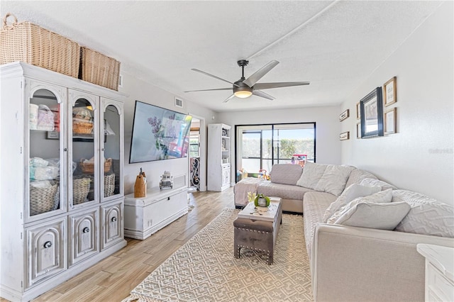 living room featuring a textured ceiling, light hardwood / wood-style floors, and ceiling fan