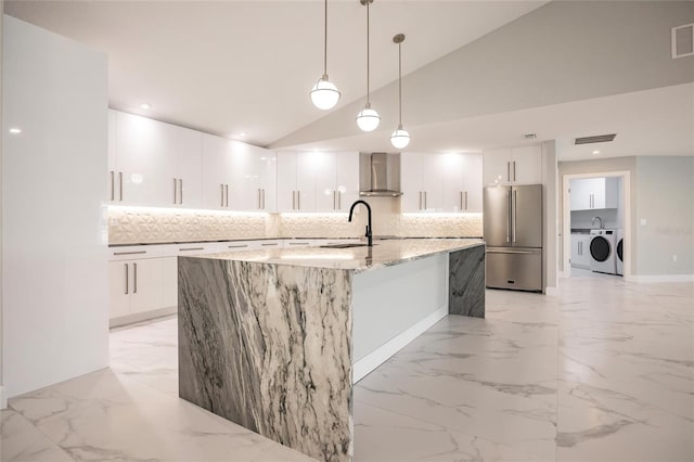 kitchen with wall chimney exhaust hood, pendant lighting, vaulted ceiling, high end fridge, and white cabinets