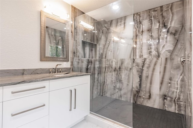 bathroom featuring vanity, a textured ceiling, and tiled shower