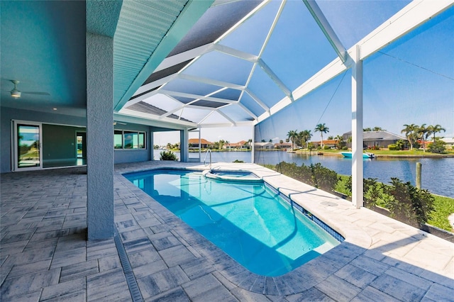 view of pool with glass enclosure, a water view, ceiling fan, an in ground hot tub, and a patio