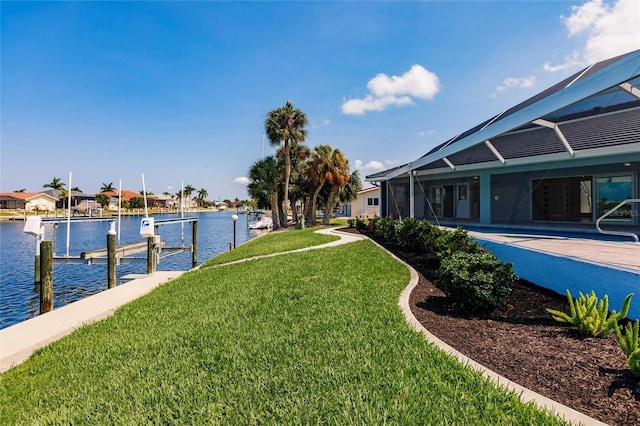 view of yard with a water view, a dock, and a lanai