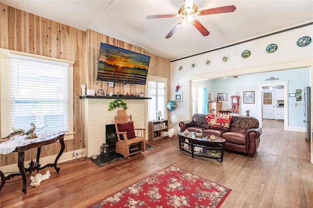 living room with ceiling fan, wooden walls, and hardwood / wood-style flooring