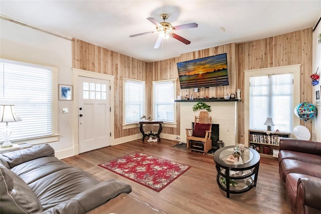 living room with hardwood / wood-style flooring, wooden walls, and ceiling fan