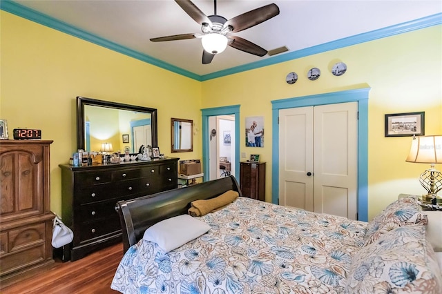 bedroom featuring dark hardwood / wood-style floors, ceiling fan, a closet, and crown molding