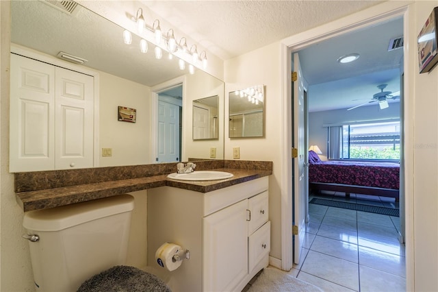 bathroom featuring vanity with extensive cabinet space, toilet, ceiling fan, tile flooring, and a textured ceiling