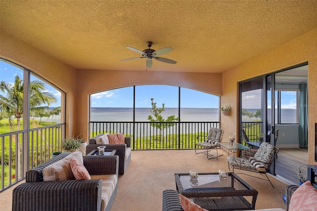 sunroom / solarium featuring plenty of natural light, ceiling fan, and a water view