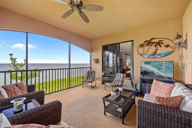 sunroom with a water view, plenty of natural light, ceiling fan, and lofted ceiling