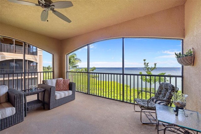 sunroom / solarium with ceiling fan and a water view