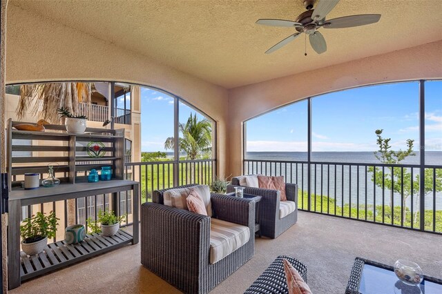 sunroom / solarium with ceiling fan and a water view