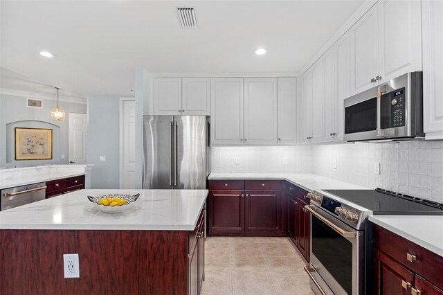 kitchen featuring a center island, hanging light fixtures, appliances with stainless steel finishes, backsplash, and light tile floors