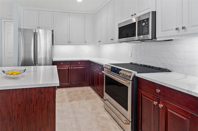 kitchen with light stone countertops, tasteful backsplash, light tile flooring, and stainless steel appliances