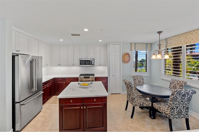 kitchen with backsplash, a notable chandelier, high quality appliances, light tile floors, and pendant lighting