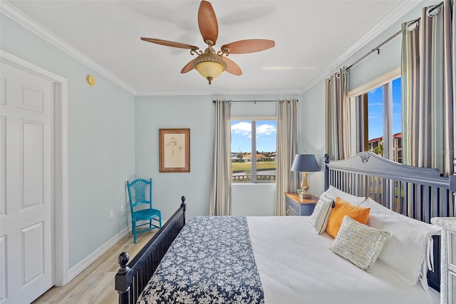 bedroom featuring light wood-type flooring, ornamental molding, and ceiling fan