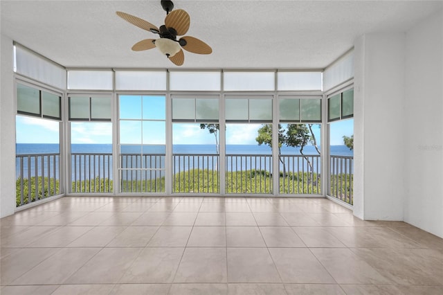 unfurnished sunroom with a healthy amount of sunlight, ceiling fan, and a water view