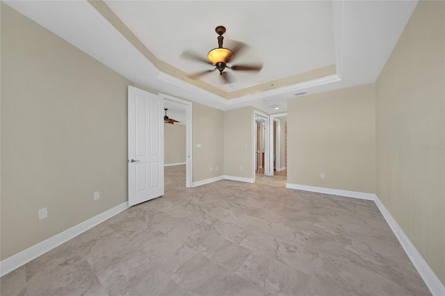 unfurnished room with tile floors, ceiling fan, and a tray ceiling