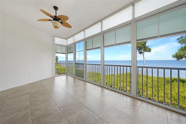 empty room with a textured ceiling, ceiling fan, light tile floors, and a water view