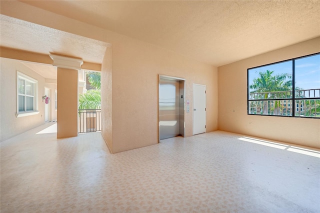 spare room featuring elevator and a textured ceiling